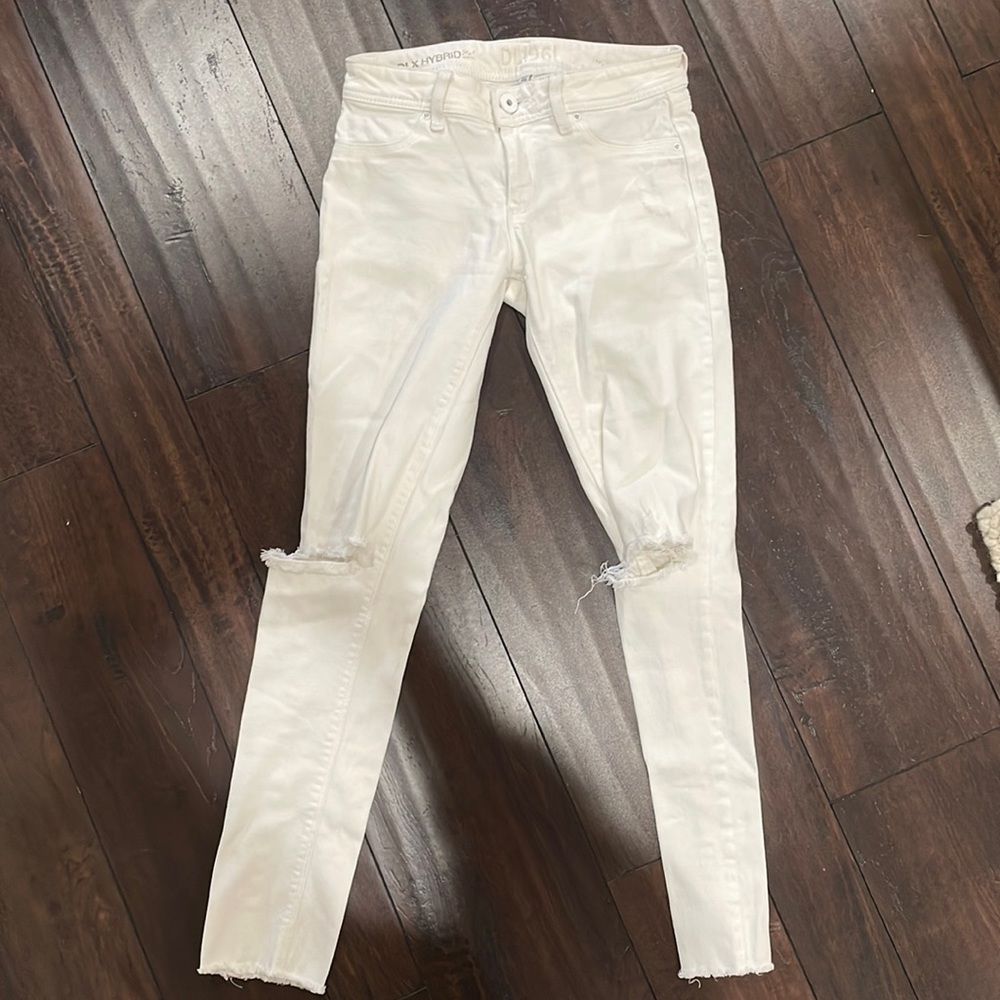 DL1961 raw hem white skinny jeans with distressing at both knees and throughout